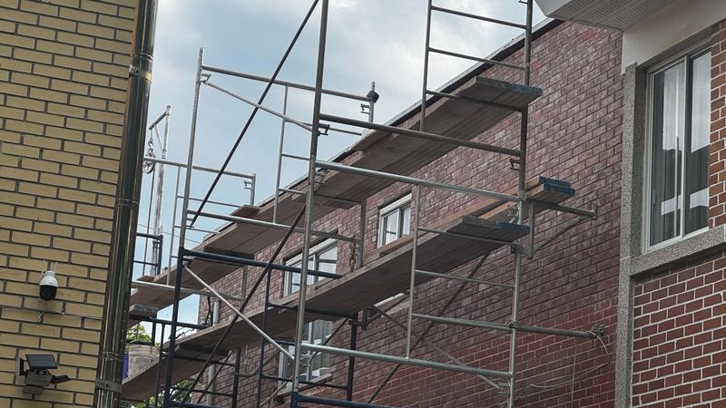 Échafaudage monté sur deux étages devant une façade de brique